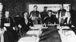 Am 20. Juli 1933 wurde zwischen dem Deutschen Reich und dem Heiligen Stuhl in Rom das Reichskonkordat unterzeichnet, durch das zum erstenmal in der Geschichte für das ganze deutsche Reich die Beziehungen der katholischen Kirche zum Staat geregelt werden. Die Unterzeichnung vollzog für Deutschland der Vizekanzler Franz von Papen, für den Heiligen Stuhl der Kardinal Staatssekretär Eugenio Pacelli. Von links nach rechts: Vizekanzler Franz von Papen, (2.v.l.) Kardinal Staatssekretär Eugenio Pacelli und Ministerialdirektor Dr. Buttmann während des Unterzeichnungsaktes. / Bundesarchiv, Bild 183-R24391 (CC BY-SA 3.0)